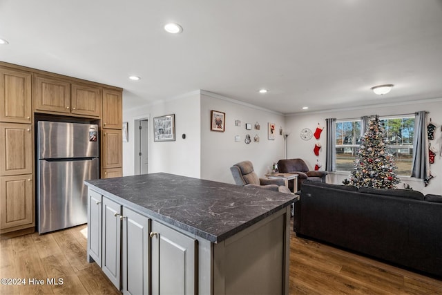 kitchen with stainless steel refrigerator, crown molding, hardwood / wood-style floors, and a kitchen island