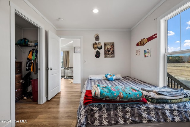 bedroom with a closet, hardwood / wood-style floors, and crown molding