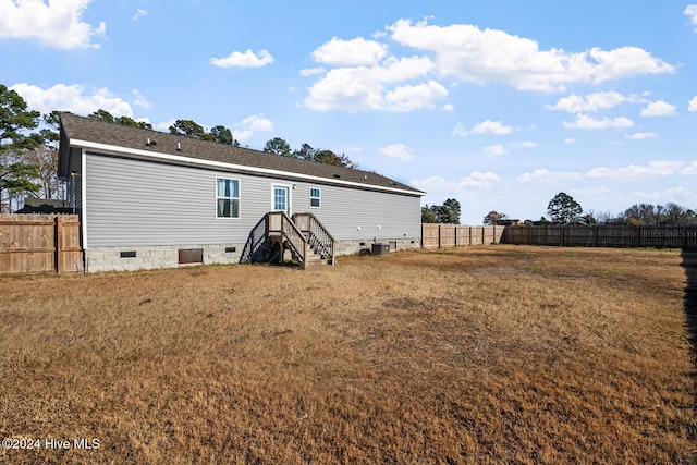 rear view of house featuring a yard and central AC