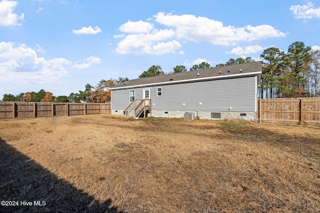 back of property featuring a yard and central AC