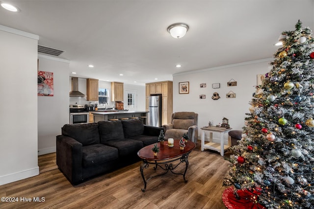 living room featuring hardwood / wood-style flooring, crown molding, and sink