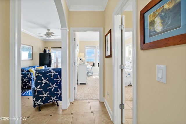 hall with light tile patterned floors, crown molding, and a wealth of natural light