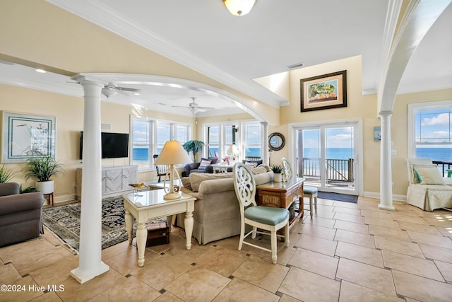 living room with decorative columns, crown molding, a water view, and a healthy amount of sunlight