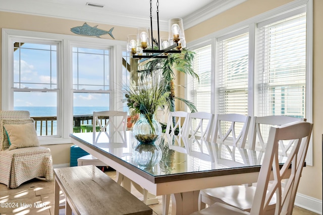 dining area featuring ornamental molding, a chandelier, and a water view