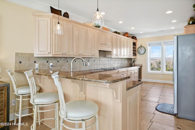 kitchen with kitchen peninsula, a breakfast bar area, stainless steel fridge, and decorative light fixtures