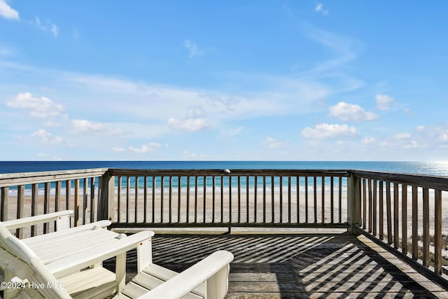 wooden deck featuring a water view and a view of the beach