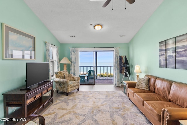 living room featuring ceiling fan, vaulted ceiling, a textured ceiling, and light wood-type flooring