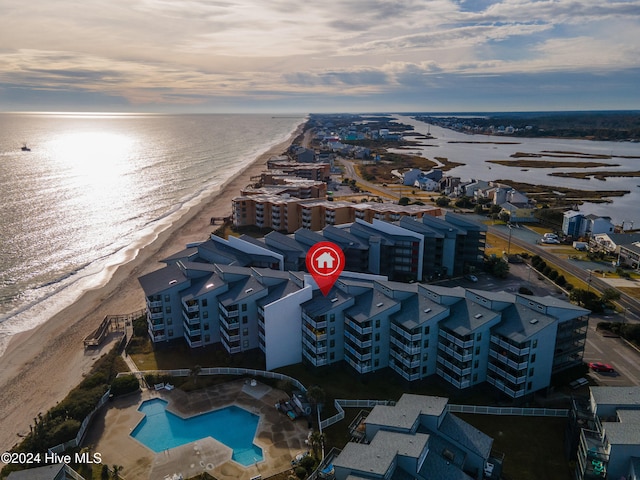 aerial view at dusk with a water view and a beach view