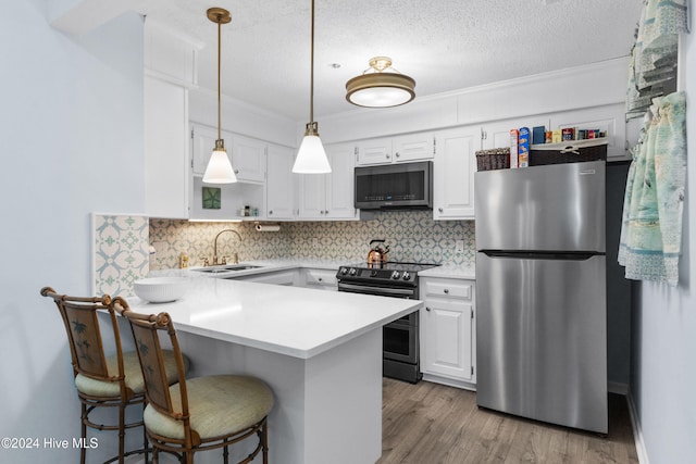 kitchen featuring sink, a breakfast bar, appliances with stainless steel finishes, white cabinets, and kitchen peninsula