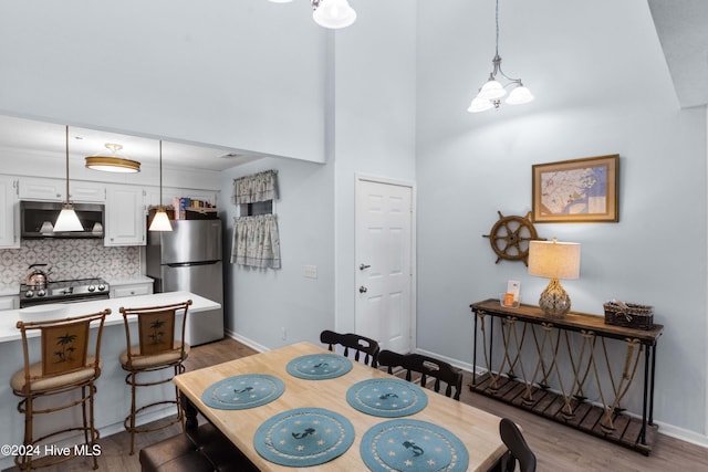 dining space with a towering ceiling and light hardwood / wood-style flooring