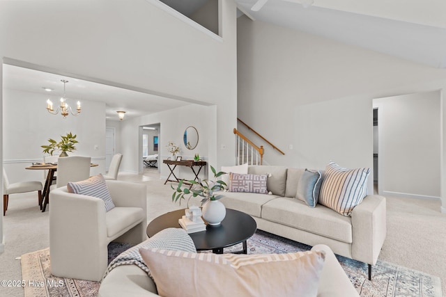 living area with high vaulted ceiling, light colored carpet, baseboards, stairs, and an inviting chandelier