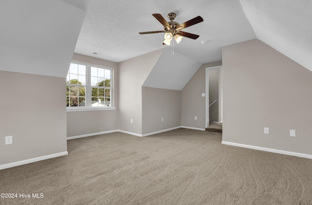 additional living space with a textured ceiling, ceiling fan, carpet flooring, and lofted ceiling