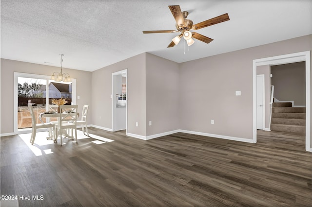 unfurnished dining area with ceiling fan with notable chandelier, a textured ceiling, and dark hardwood / wood-style flooring