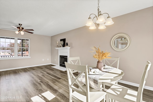 dining area with ceiling fan with notable chandelier and dark hardwood / wood-style floors