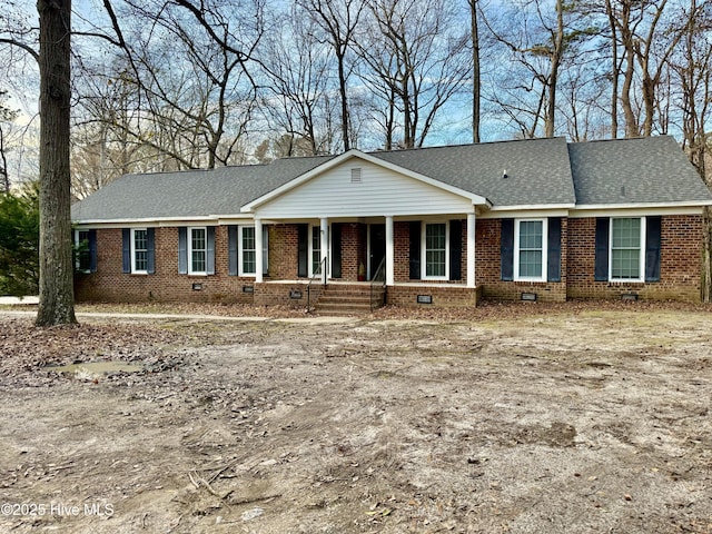 single story home featuring covered porch, roof with shingles, brick siding, and crawl space