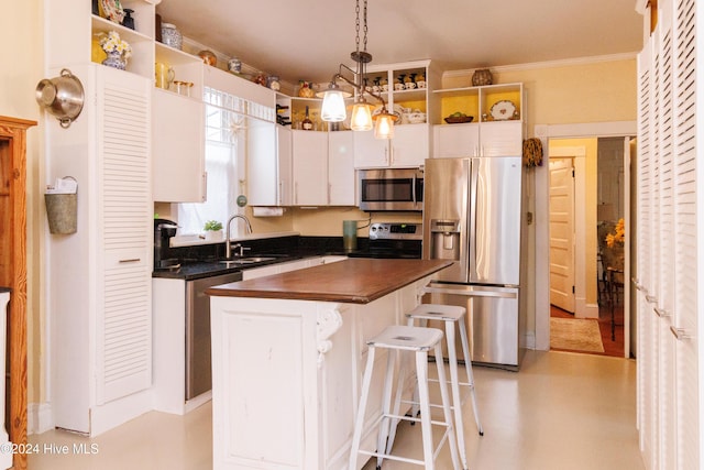 kitchen with white cabinetry, sink, stainless steel appliances, pendant lighting, and ornamental molding