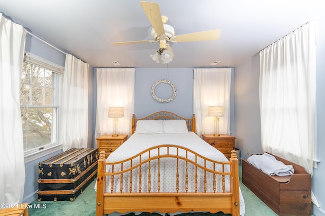 carpeted bedroom with multiple windows and ceiling fan