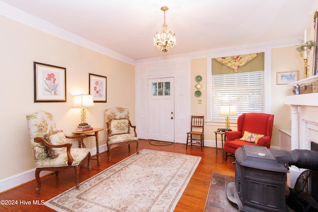 living area with hardwood / wood-style floors, crown molding, a fireplace, and a chandelier