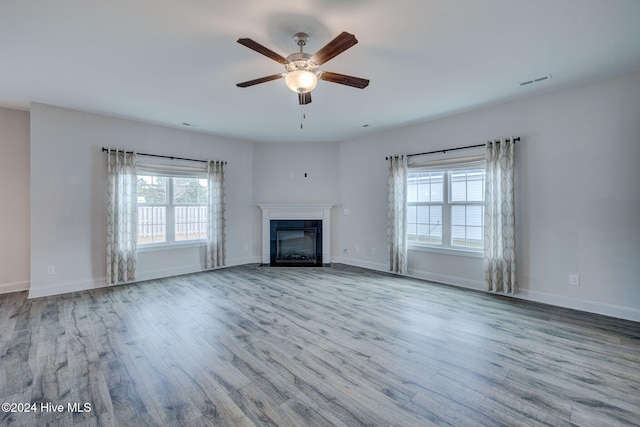 unfurnished living room featuring light hardwood / wood-style floors, ceiling fan, and a healthy amount of sunlight