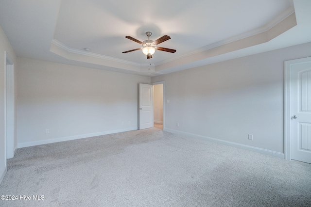 carpeted spare room with a tray ceiling and ornamental molding