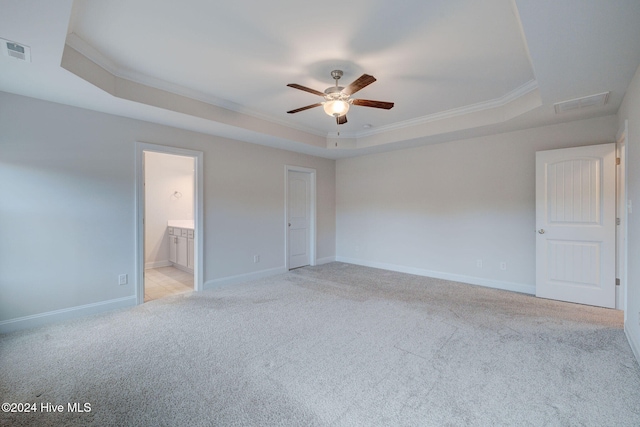 spare room featuring ceiling fan, ornamental molding, light carpet, and a tray ceiling