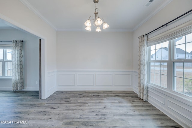 unfurnished dining area featuring light wood-type flooring, an inviting chandelier, and ornamental molding