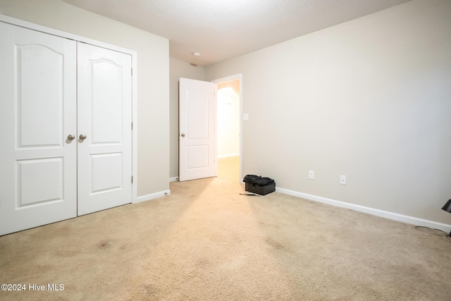 unfurnished bedroom featuring light colored carpet and a closet