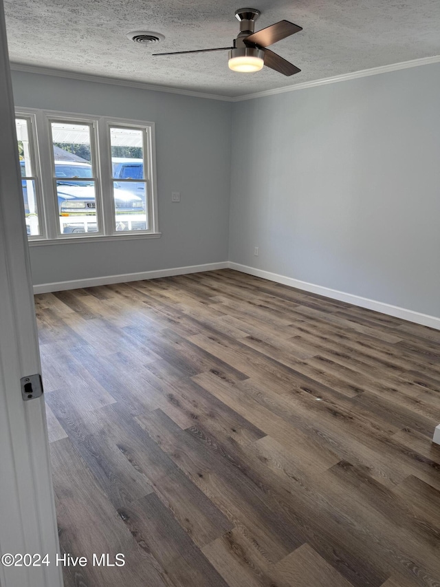 empty room featuring a textured ceiling, ceiling fan, ornamental molding, and dark wood-type flooring