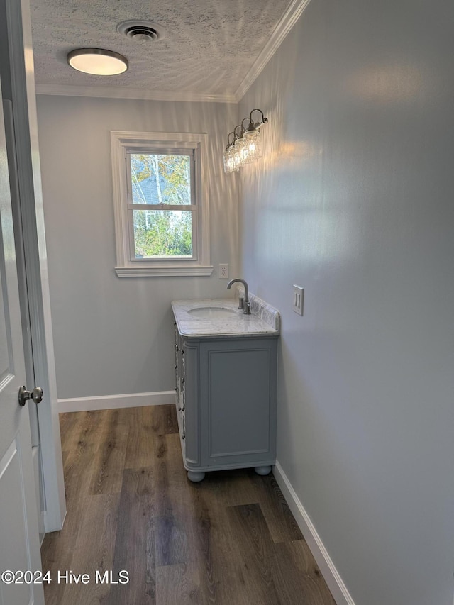 bathroom featuring a textured ceiling, vanity, wood-type flooring, and crown molding