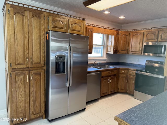 kitchen with sink, ornamental molding, a textured ceiling, light tile patterned flooring, and stainless steel appliances