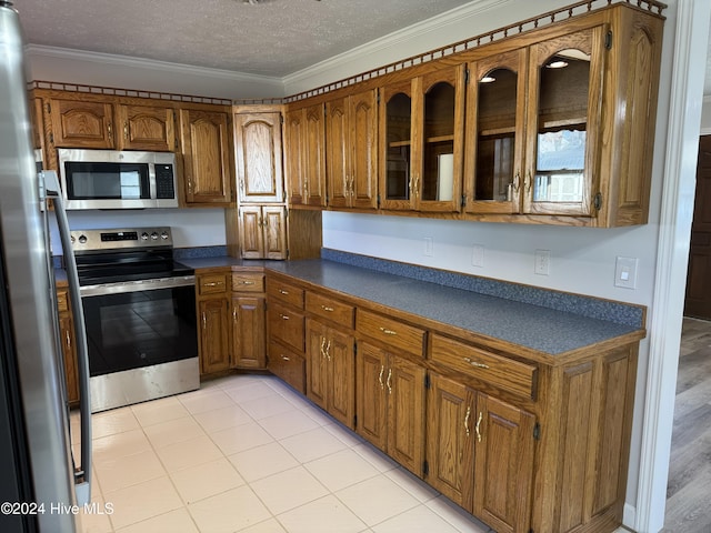 kitchen featuring ornamental molding, a textured ceiling, appliances with stainless steel finishes, and light hardwood / wood-style flooring