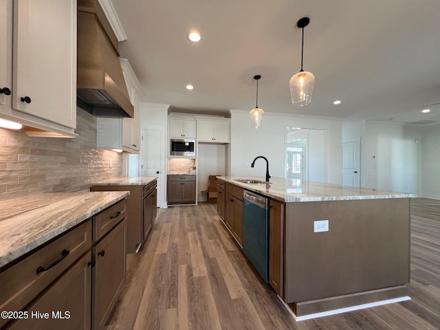 kitchen featuring appliances with stainless steel finishes, white cabinets, hanging light fixtures, a large island with sink, and custom range hood