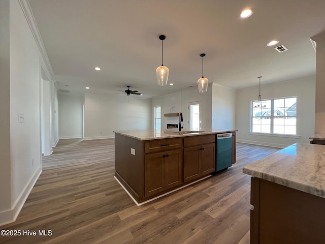 kitchen featuring decorative light fixtures, sink, stainless steel dishwasher, light stone counters, and a center island with sink