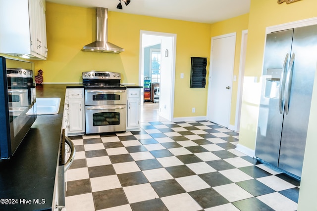 kitchen featuring white cabinets, stainless steel appliances, and wall chimney range hood