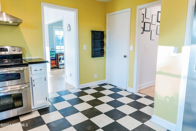 kitchen featuring electric range, white cabinetry, and extractor fan