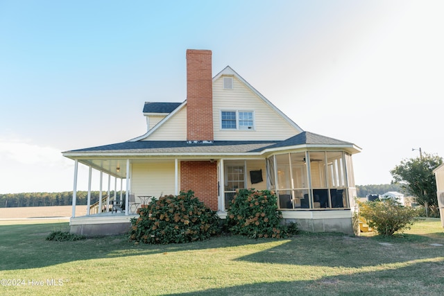 rear view of property with a sunroom and a lawn