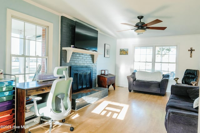 office space with crown molding, a fireplace, ceiling fan, and hardwood / wood-style flooring