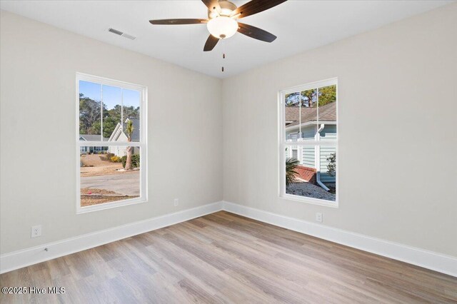 unfurnished bedroom featuring a walk in closet, a tray ceiling, a closet, ceiling fan, and light hardwood / wood-style floors