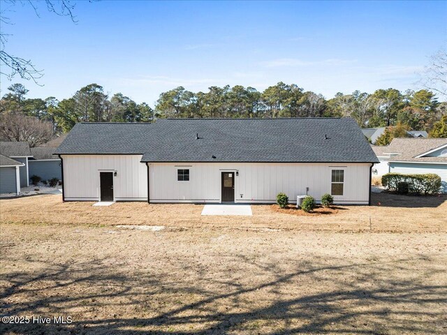 rear view of house with central AC and a yard