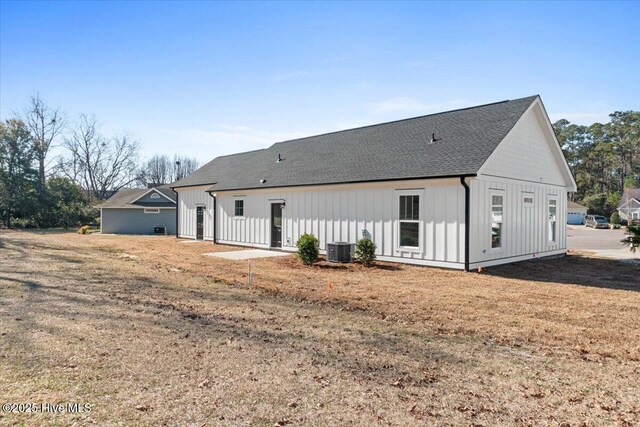 rear view of property with central AC and a lawn