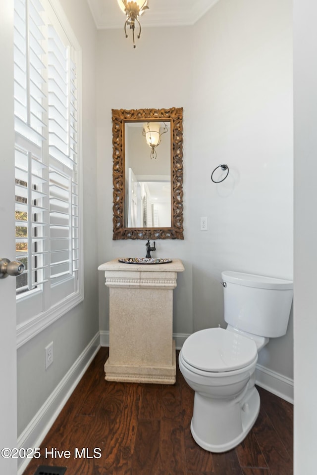 half bathroom featuring baseboards, vanity, toilet, and wood finished floors