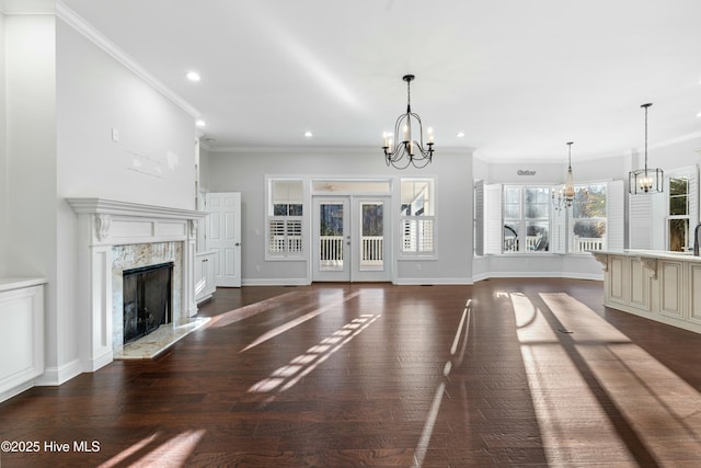 unfurnished living room with an inviting chandelier, a premium fireplace, ornamental molding, and dark wood finished floors