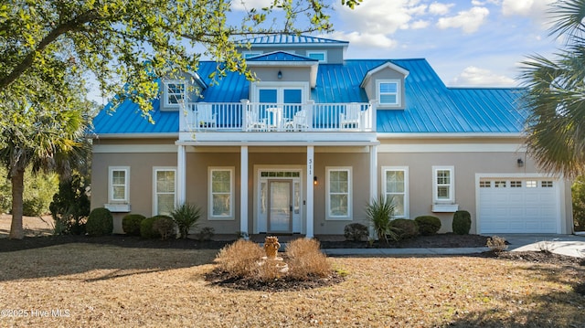 view of front of property with stucco siding, concrete driveway, an attached garage, metal roof, and a balcony