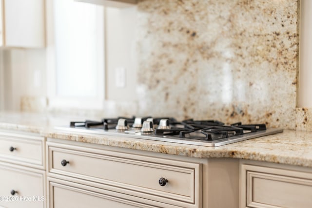 kitchen featuring stainless steel gas stovetop, light stone counters, and cream cabinetry