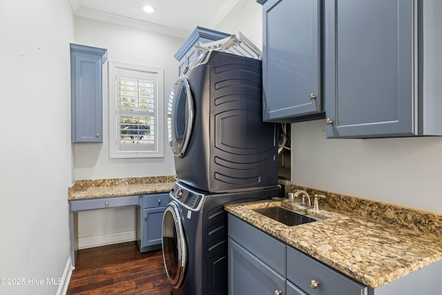 laundry area with crown molding, dark wood finished floors, cabinet space, a sink, and stacked washing maching and dryer