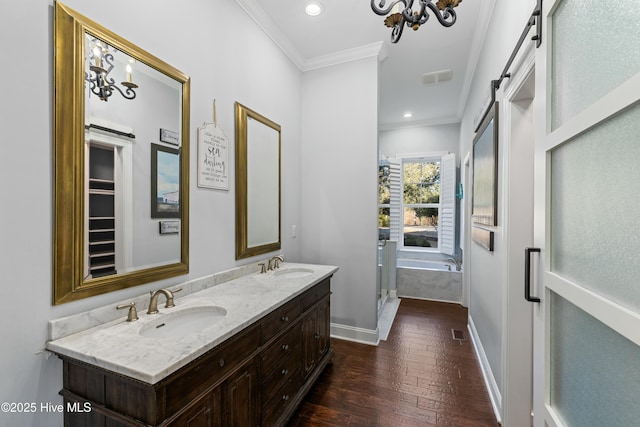 full bathroom with a sink, baseboards, double vanity, wood-type flooring, and crown molding