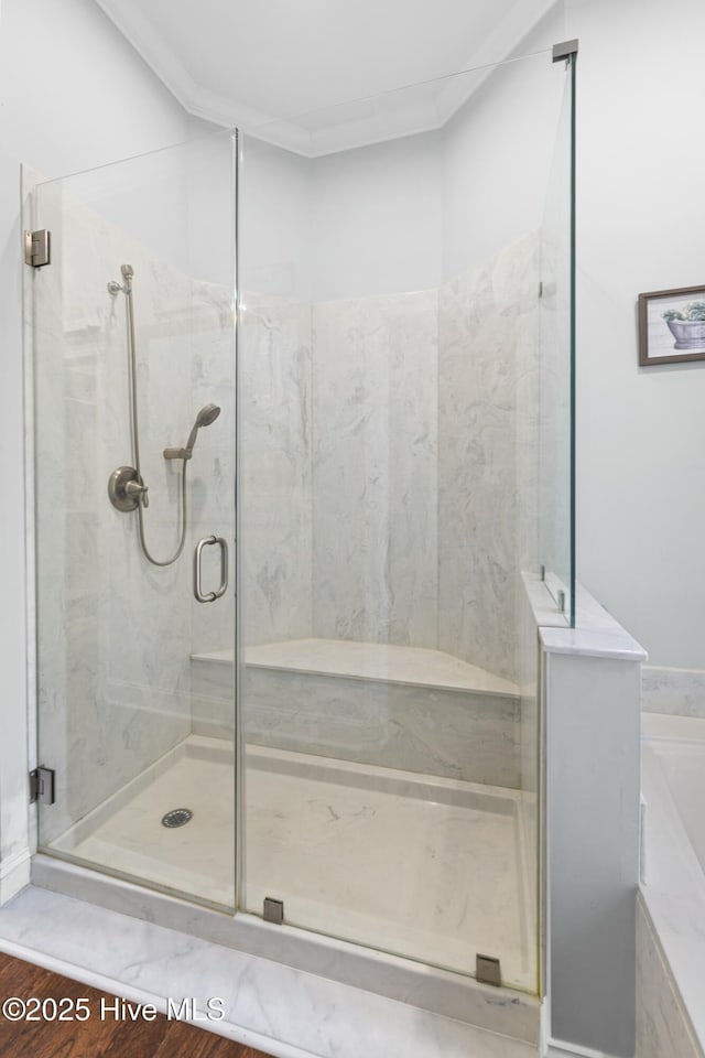 full bath featuring wood finished floors, ornamental molding, and a marble finish shower