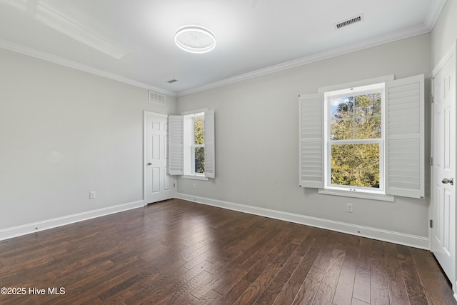 empty room with ornamental molding, visible vents, dark wood finished floors, and baseboards