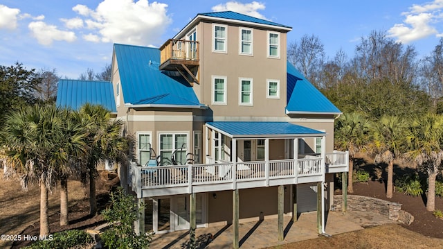 rear view of house featuring metal roof and stucco siding