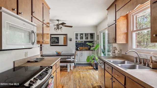 kitchen with light wood-type flooring, stainless steel appliances, a sink, and light countertops